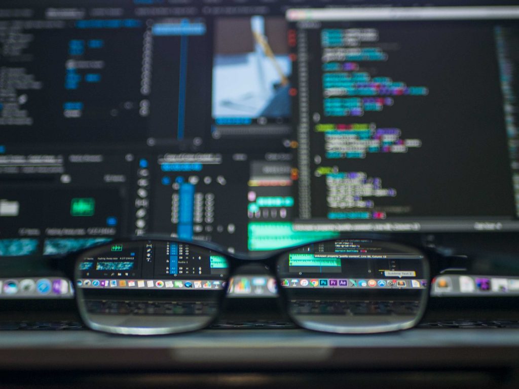Glasses in front of a computers with data and codes